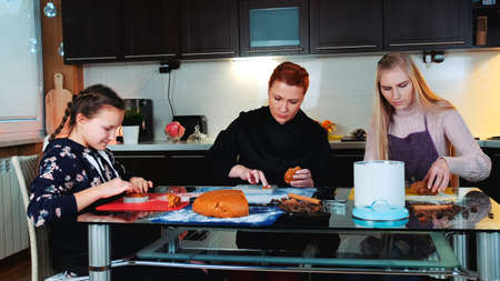 Masterclass cookies making in joyful atmosphere at home. Two women and a girl filling baking dish with pastry dough.の写真素材
