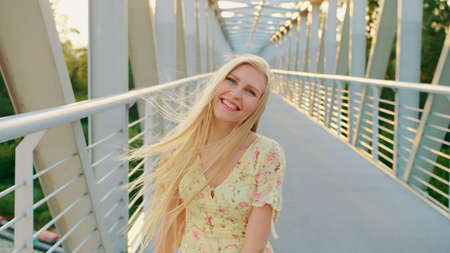 Woman looking back on bridge. Pretty blonde woman looking back at camera while running on bridge with wavy hair.の写真素材