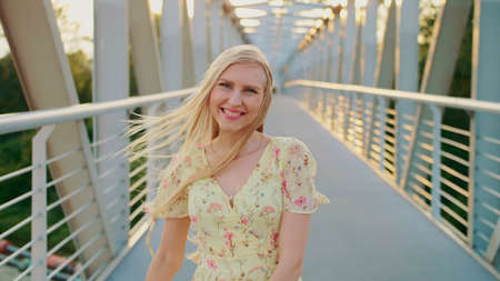 Woman throwing up hair on bridge. Back view of blonde woman running on pedestrian bridge and throwing up hair.の写真素材