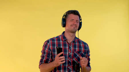 Handsome man in headphones enjoying listening to the music. He listening tracks on smartphone.の写真素材