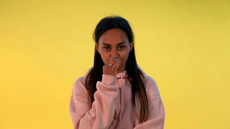 Portrait of african womans lips closing zipper on yellow background. It must be secret.の写真素材