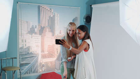 Backstage of the photo shoot: attractive black model making selfie with pretty make-up artist. They smiling and having fun.の写真素材