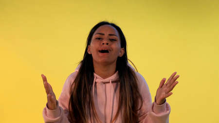 Desperate multiethnic woman spreading her hands to the sides on yellow background. She asking whyの写真素材