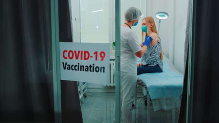 Female doctor making vaccination against the coronavirus in district hospital. Woman was vaccinated against Sars-Cov-2.の写真素材