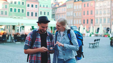 Couple of tourists using smartphone and admiring beautiful surroundings. They going sightseeing early in the morning.の写真素材