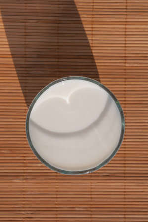 A glass of milk on a brown mat seen from above の写真素材