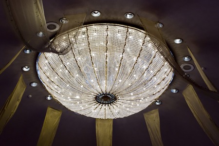 shining chandelier hanging on a ceiling in hotelの写真素材