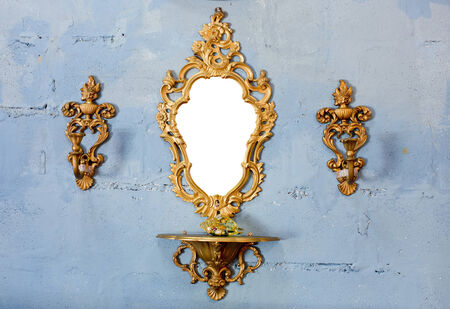 Golden vintage mirror with gold candlestick on wallの写真素材