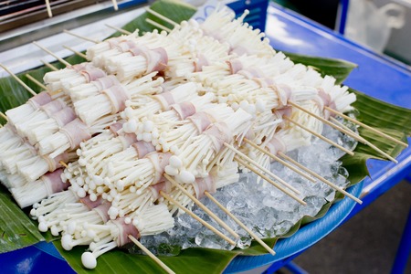 Roast bacon wrapped Flammulina Velutipes with skewer, street food in Bangkok, Thailand