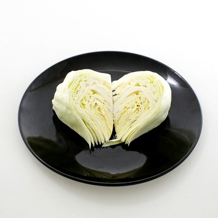 slice cabbage on black plate isolated on white backgroundの写真素材