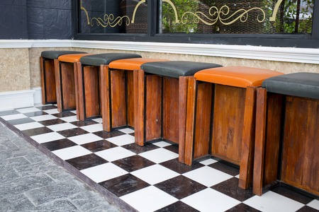 Classic wooden bar stools are lined up at an outdoor bar の写真素材