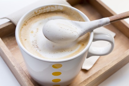 Whipping Cream on a spoon and a cup of coffee Cappuccinoの写真素材