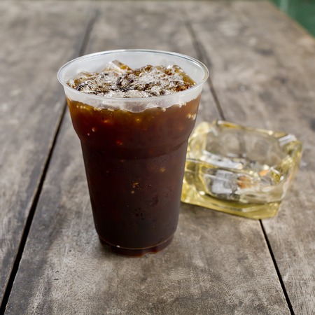 Delicious ice coffee americano  with cigarette on the old wooden table