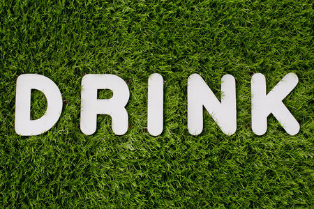 Drink text made of white wood vector design element on grass background.の写真素材