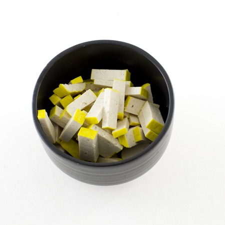 Fresh yellow tofu in black bowl isolate white backgroundの写真素材
