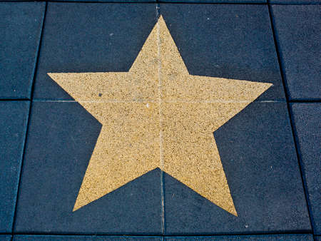 Dark blue brick floor with a painting of a big gold star.の写真素材