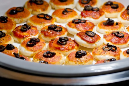 round meat pies with topping black olive sliced on buffet lineの写真素材