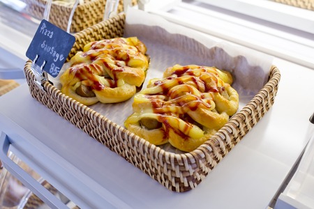 Tasty pizza sausage topping tomatoes sauce in basket with name and price on black sign for sell