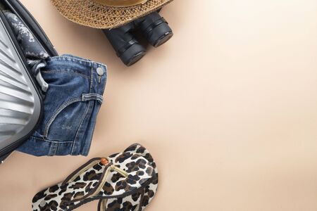 Flat lay  suitcase with binoculars, hat, jeans and saddles on pastelの写真素材