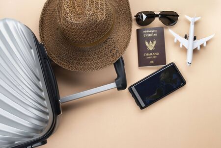 Flat lay  suitcase with brown hat, mini airplane, Thailand Passport, sunglasses and phone on pastelの写真素材