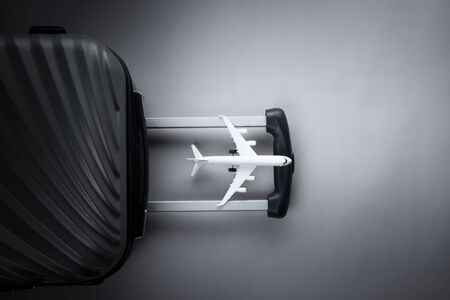 Flat lay grey suitcase with mini airplane on grey background. travel concept - Imageの写真素材