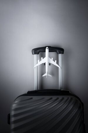 Flat lay grey suitcase with mini airplane on grey background. travel concept - Imageの写真素材