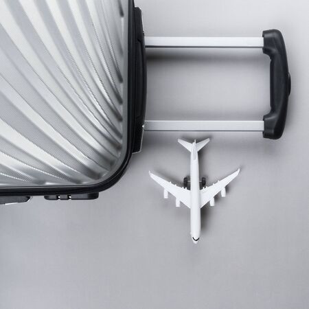 Flat lay grey suitcase with mini airplane on grey background. travel concept - Imageの写真素材