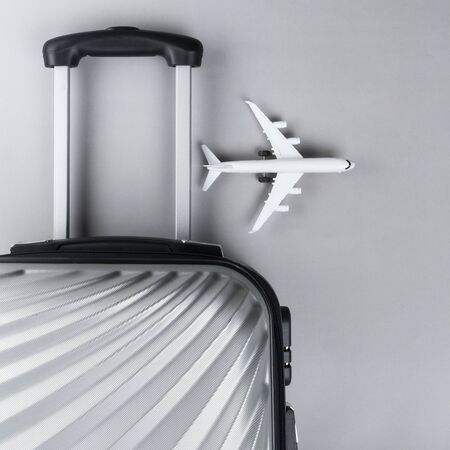 Flat lay grey suitcase with mini airplane on grey background. travel concept - Imageの写真素材