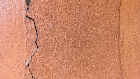 Cracks on the old orange wall and peeling paint.の写真素材