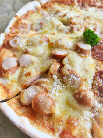 Crispy thin crust pizza topped with cheese and sausage, eight pieces placed on a wooden tray.の写真素材