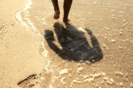 Cropped photo of feet of man legs on the sea sandの写真素材
