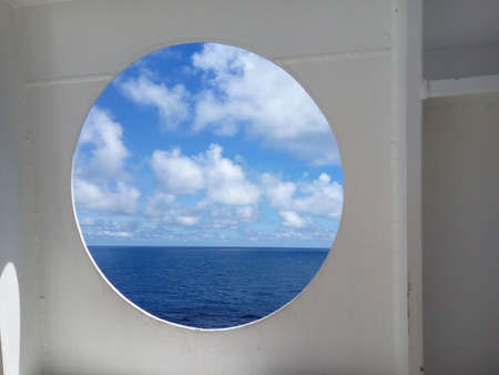 Porthole of a ocean liner with blue skyの写真素材