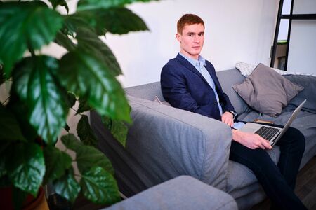 Mature European man using laptop on the couchの写真素材