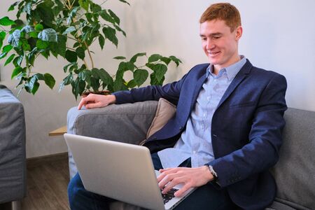 Mature European man using laptop on the couchの写真素材