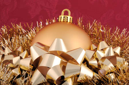 A gold Christmas ornament surrounded by garland and bows.の写真素材