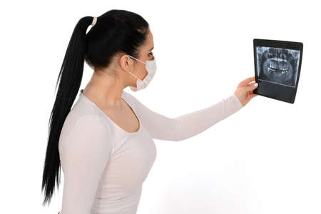 X-ray of a human jaw in the hands of the dentist. Beautiful girl holding x-ray, wearing protective...