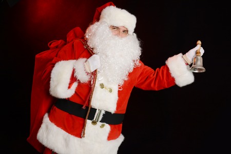 Traditional Santa Claus ringing on a bell, caring sack full of presentsの写真素材