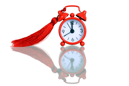 Old red alarm clock with tassel, Red round alarm clock shows 5 minutes to midnightの写真素材