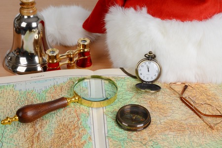 Santa Claus equipment. Magnificent glass, spy glass, compass, glasses, hat, binocular, bell on mapの写真素材