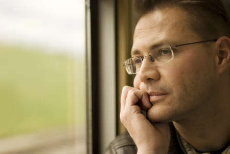 Thinking man looking out of window,  in the trainの写真素材