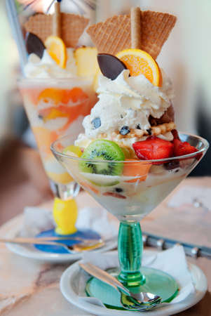Tasty ice-cream with tropical fruits, waffles and chocolate on the table in cafe