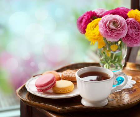Cup of coffee with macaroons on a table with flowers ranunculusの写真素材