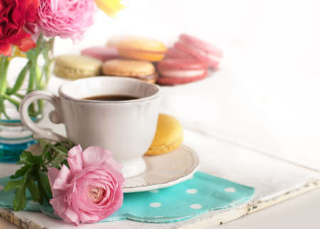 Cup of coffee with macaroons on a table with flowers ranunculusの写真素材