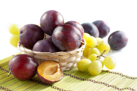 Fresh ripe plums and grapes in wooden bowl, selective focusの写真素材