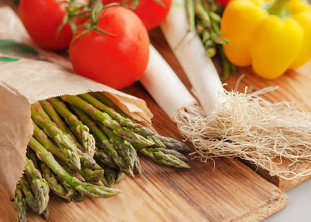 Green  asparagus and tomatoes on a wooden tableの写真素材