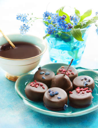 Cup of coffee, assortment of fine chocolates dark, milk chocolate and blue flowers on a table