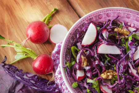 Raw red cabbage salad with radish, basil and walnut, wooden tableの写真素材