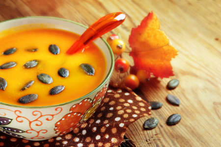 Autumn pumpkin soup with seeps on a wood tableの写真素材