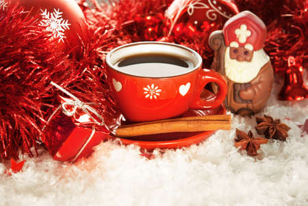 Cup of coffee with chocolate Saint Nicholas and gift on a winter backgroundの写真素材
