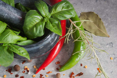 Bunch fresh basil in mortar with Pestle, Red Hot Chili Peppers, herbs and spices on a tableの写真素材